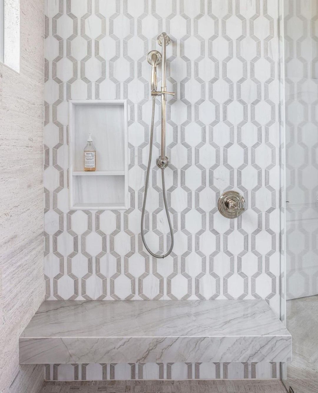 A shower with a geometric pattern on the wall and a shower head.