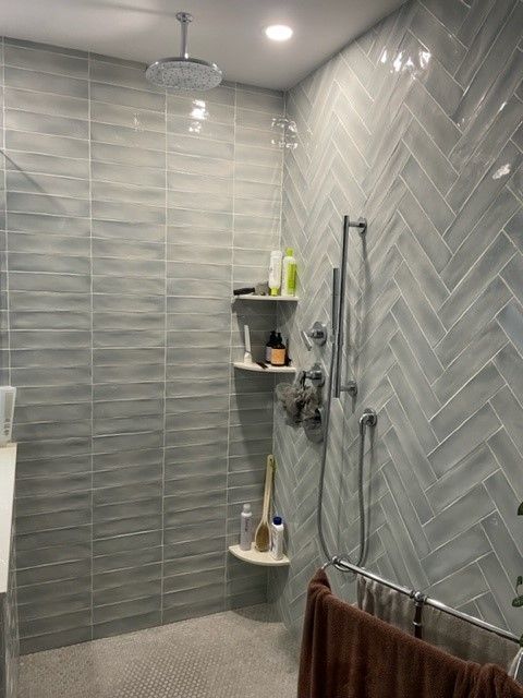 A bathroom with a walk in shower and a ceiling fan.