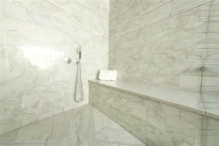 A bathroom with a walk in shower and a bench.