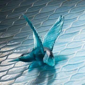 A blue bird is flying on a tile floor