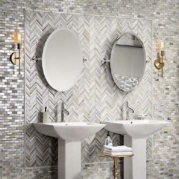 A bathroom with two sinks , two mirrors and a herringbone tile wall.