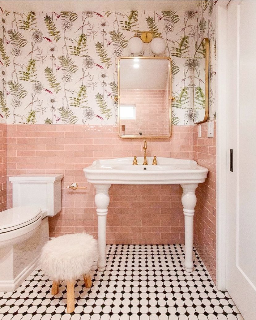 A bathroom with pink tiles , a sink , a toilet and a mirror.