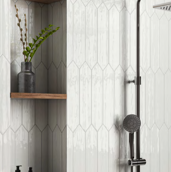 A bathroom with white tiles and a shower head.