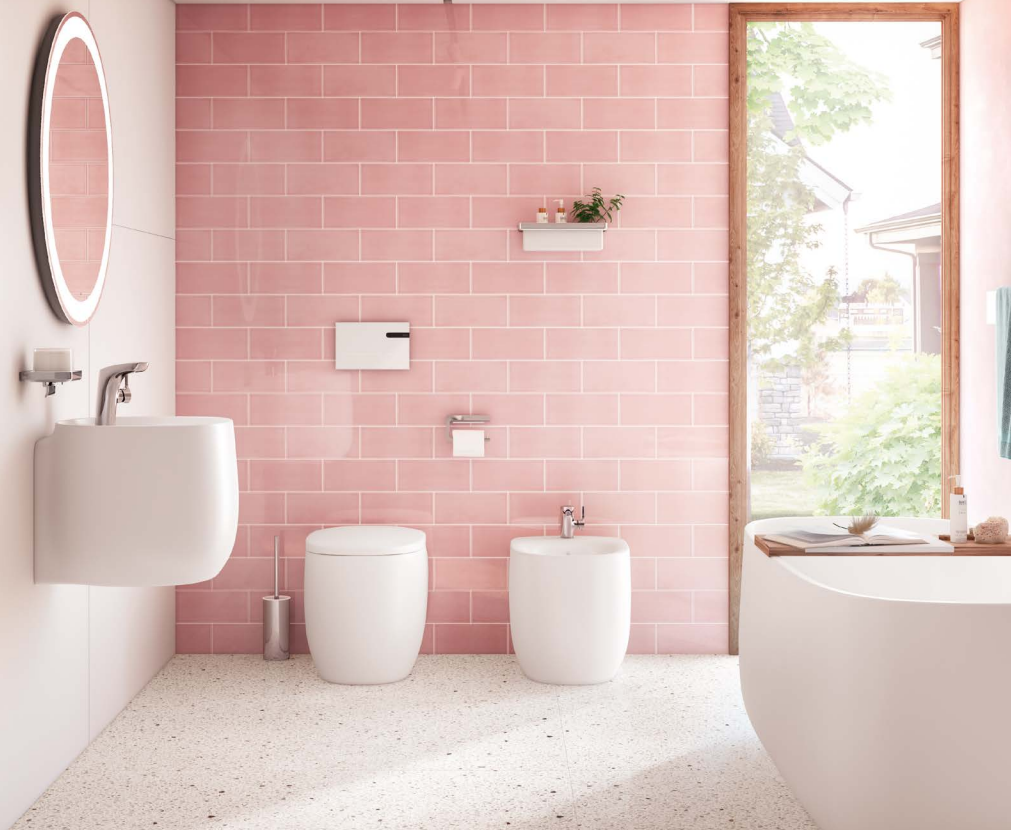 A bathroom with pink tiles , a sink , toilet , bidet and bathtub.