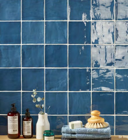 A bathroom with blue tiles and soaps on a counter