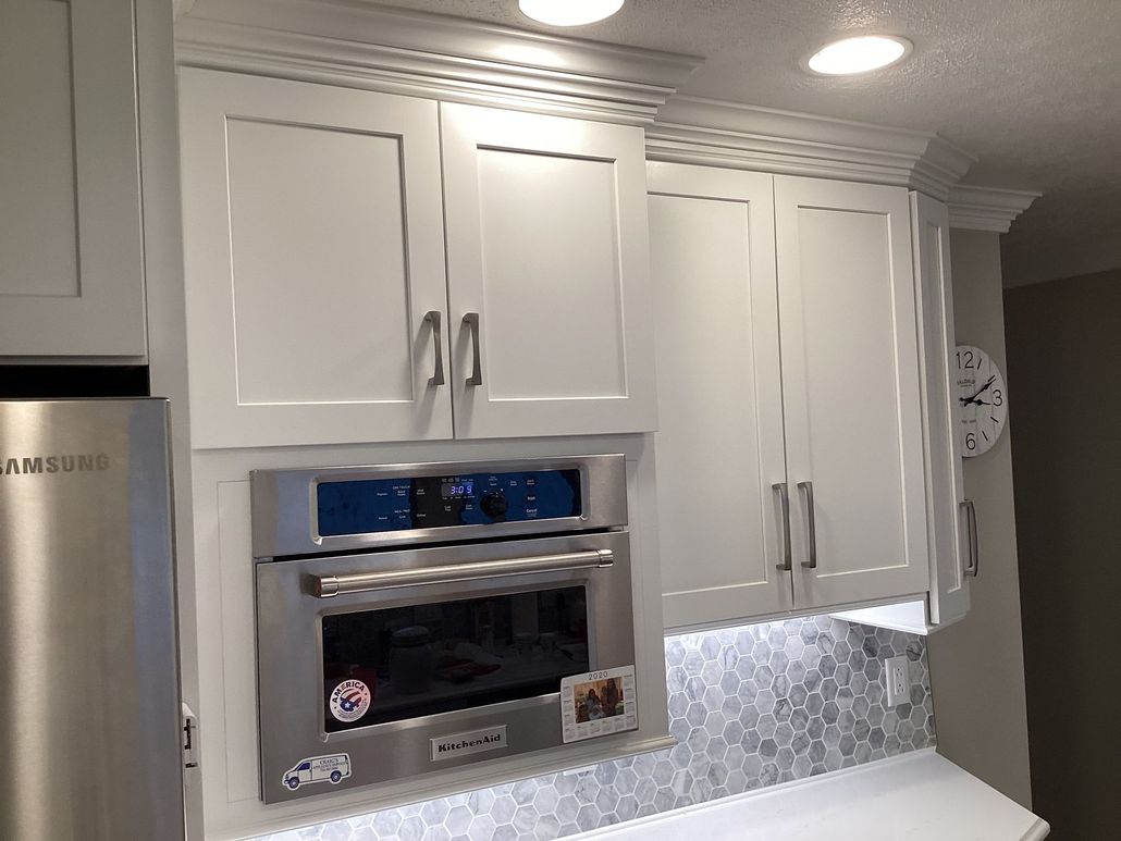 Light wood kitchen with island, granite countertops, built-in appliances, and a window.