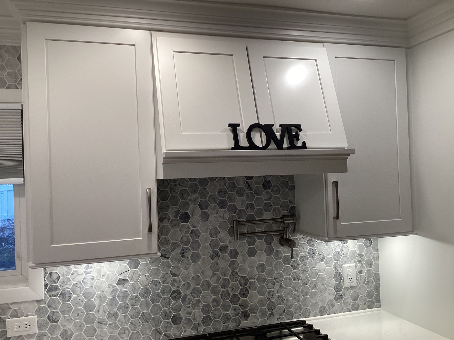 White kitchen cabinets with gray tile backsplash and stove. 