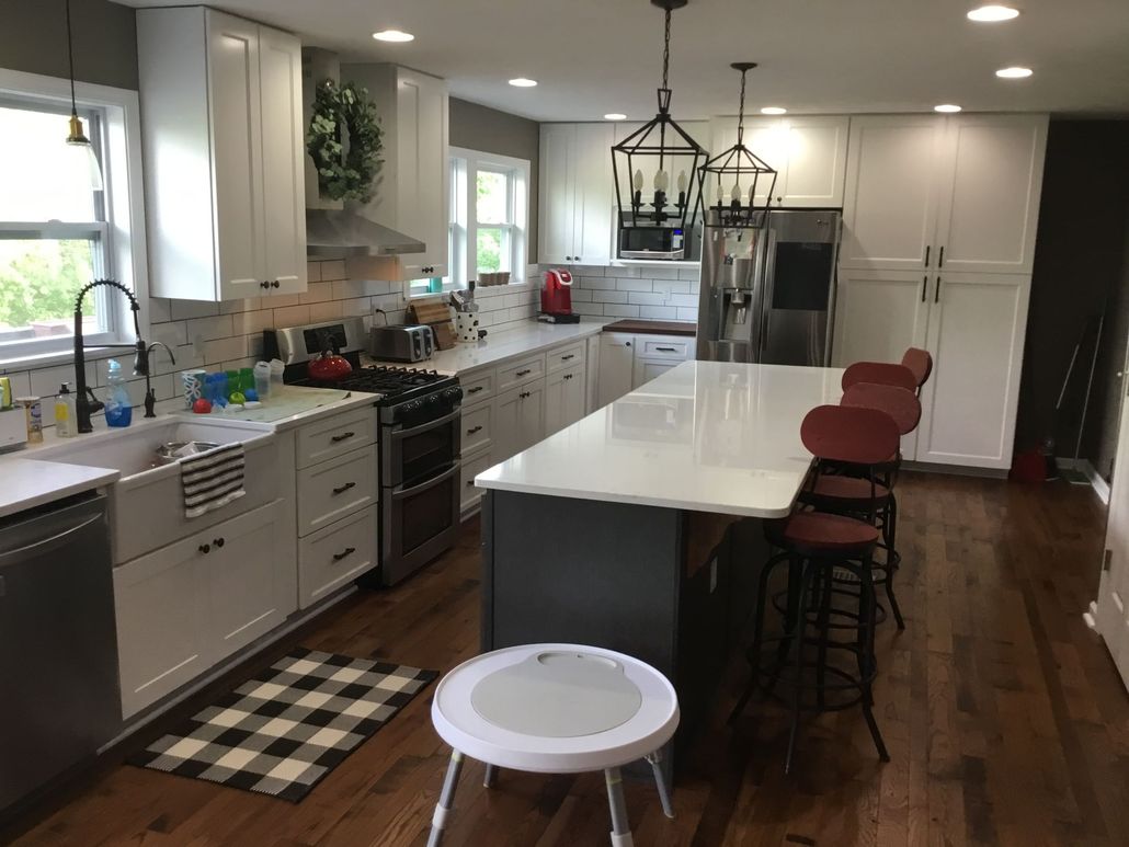 Modern kitchen with large stainless steel refrigerator, island with seating, and pendant lights.