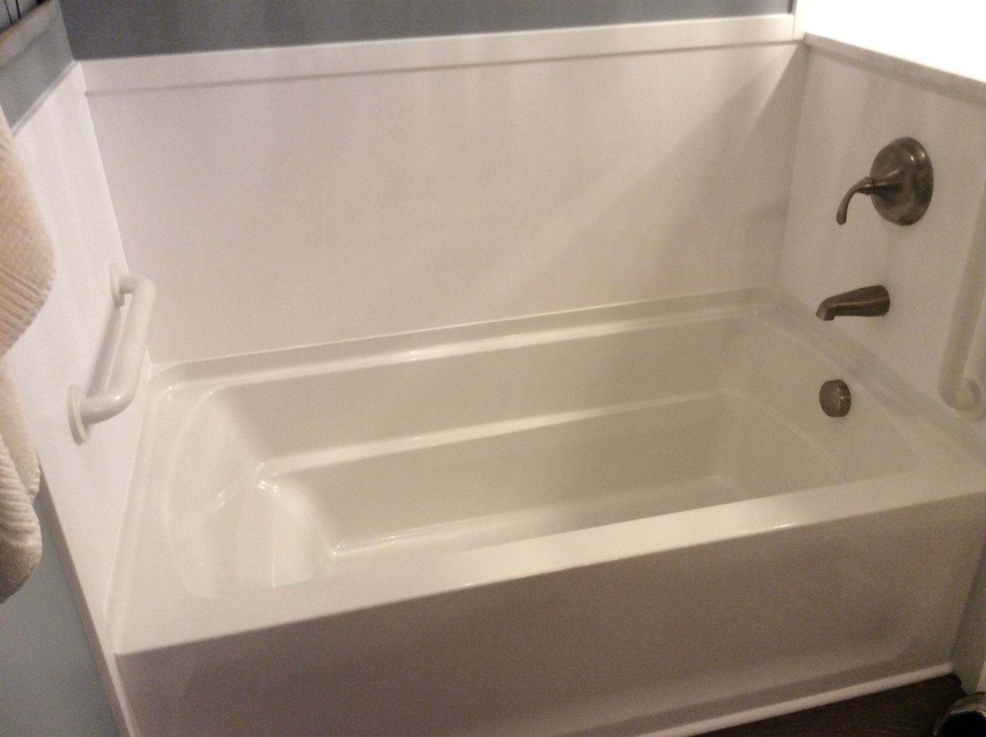 White bathtub with grab bar and faucet.