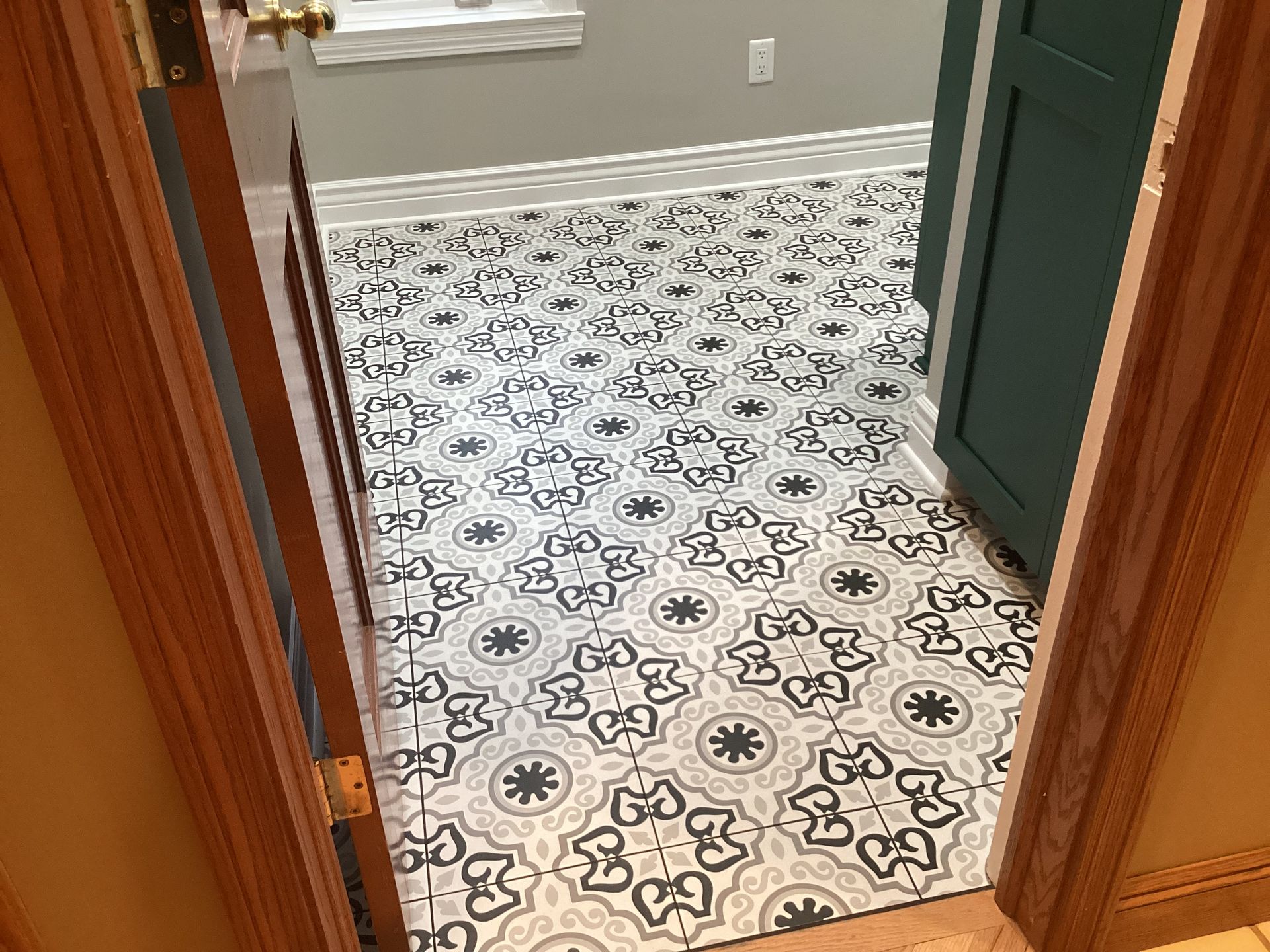 View through a doorway into a room with patterned tile flooring and a green cabinet.