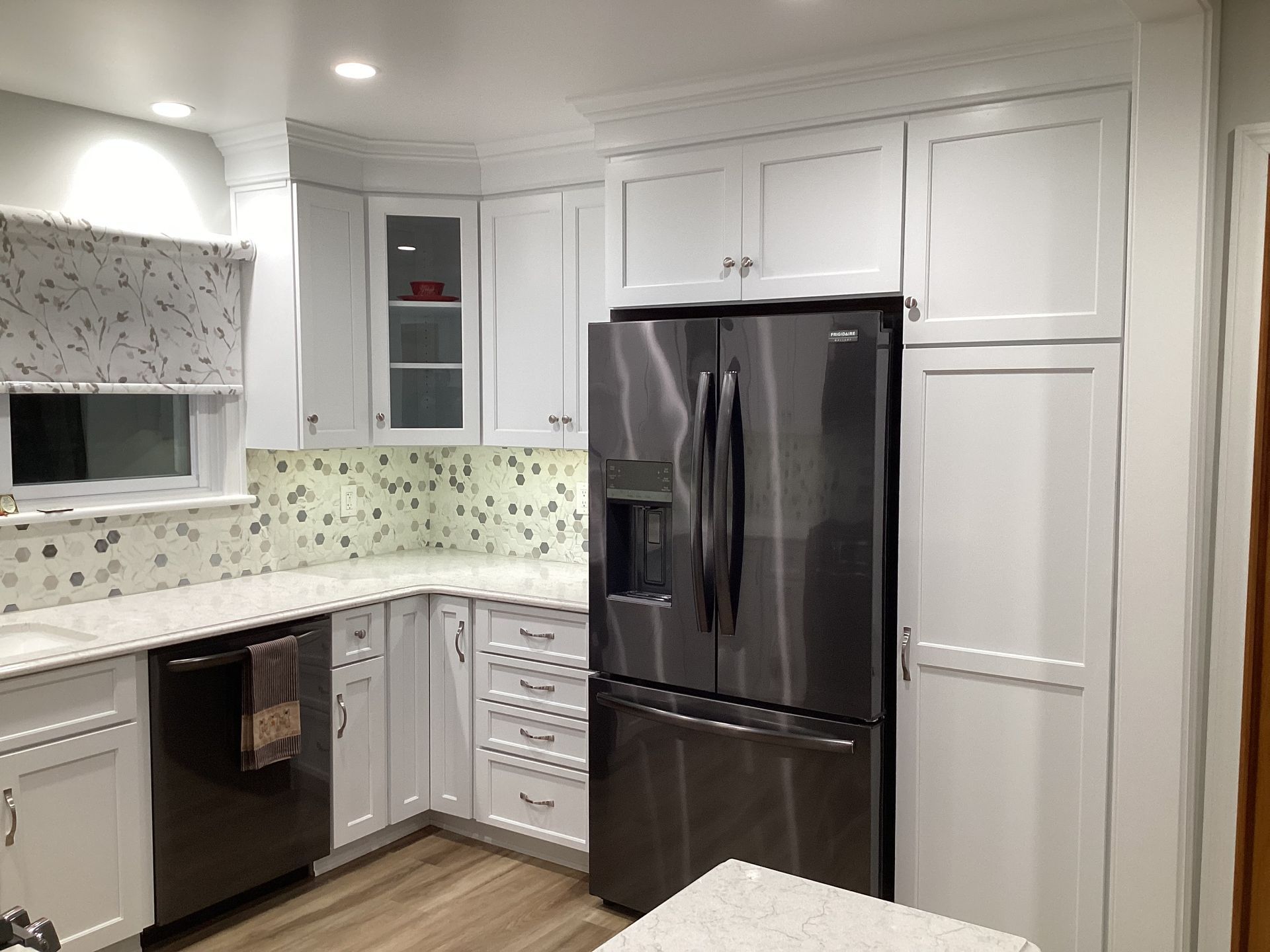 White kitchen with stainless steel appliances and light-colored countertops and backsplash.