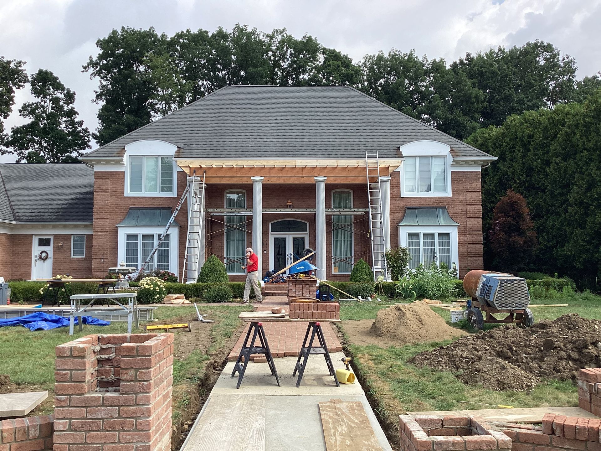 A two-story brick house with construction ongoing; a worker is present.