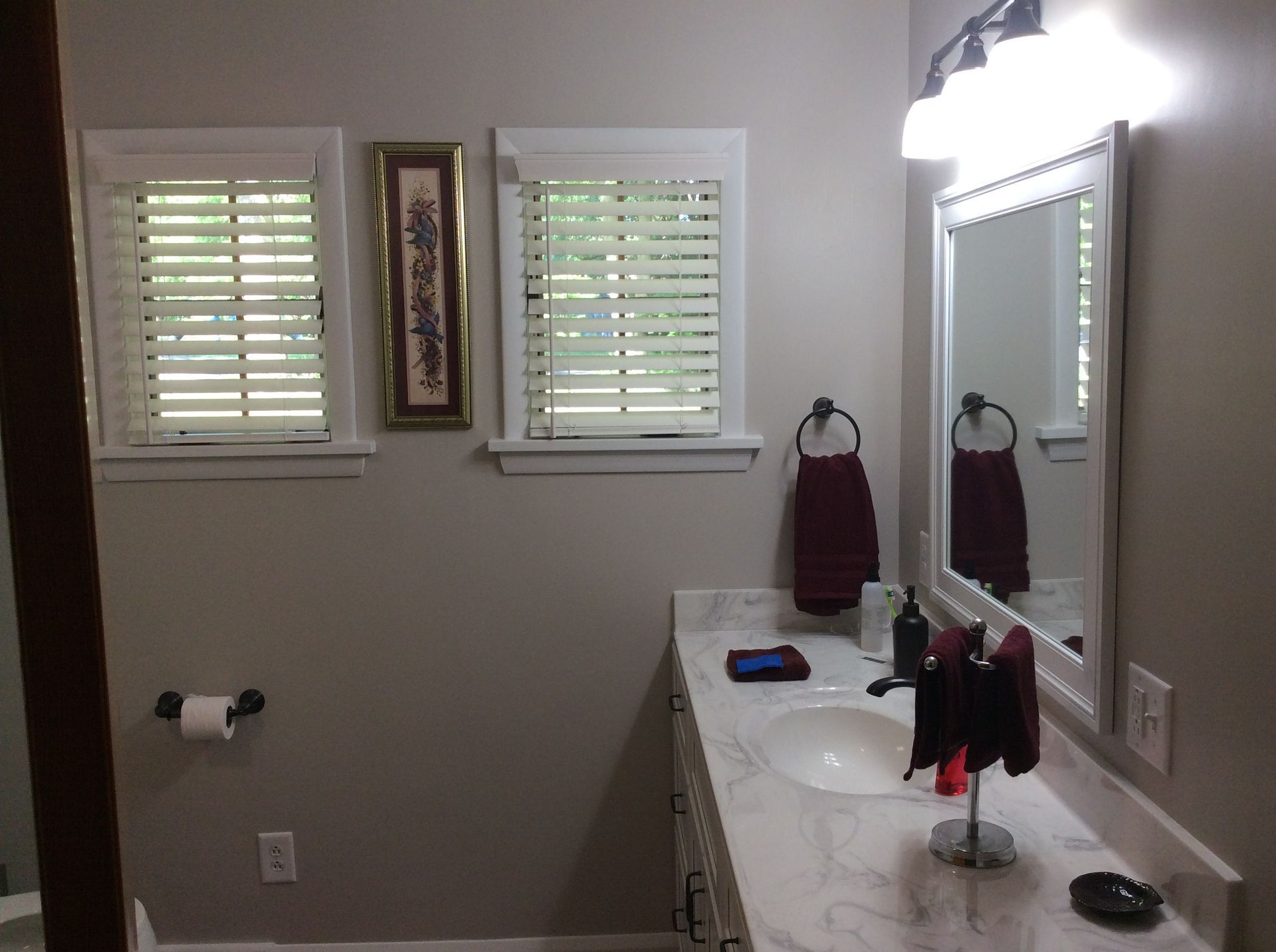 Bathroom with two windows, a mirror, vanity, and a towel rack.