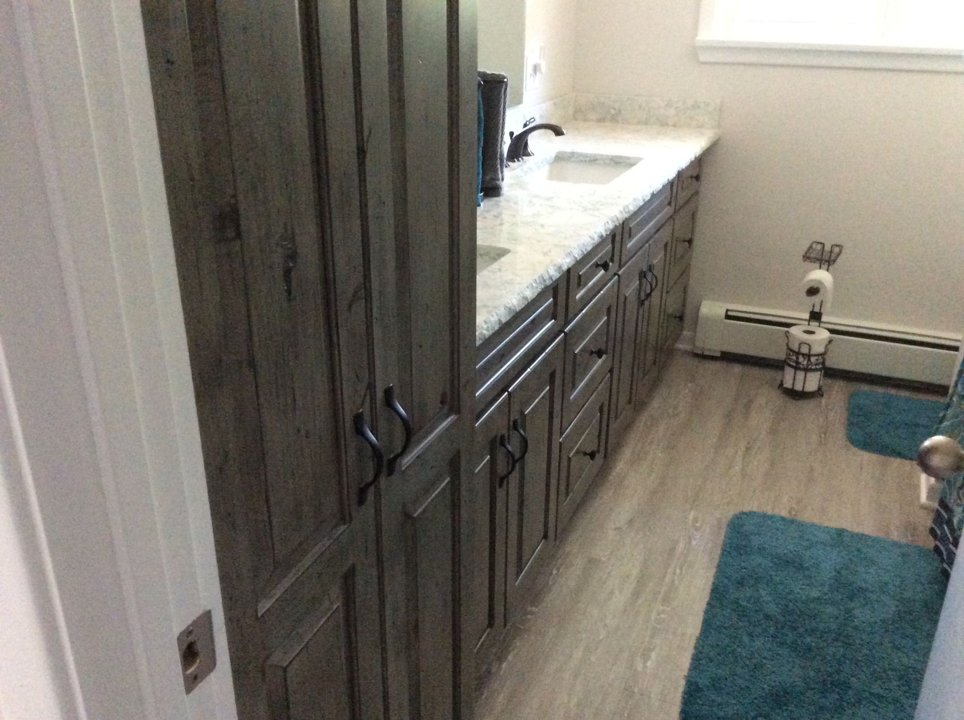 Bathroom with gray cabinets, white countertop, and turquoise rug.