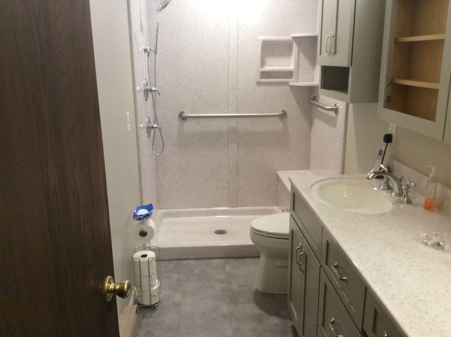 Accessible bathroom with a walk-in shower, grab bar, toilet, and vanity. Gray walls and cabinetry.
