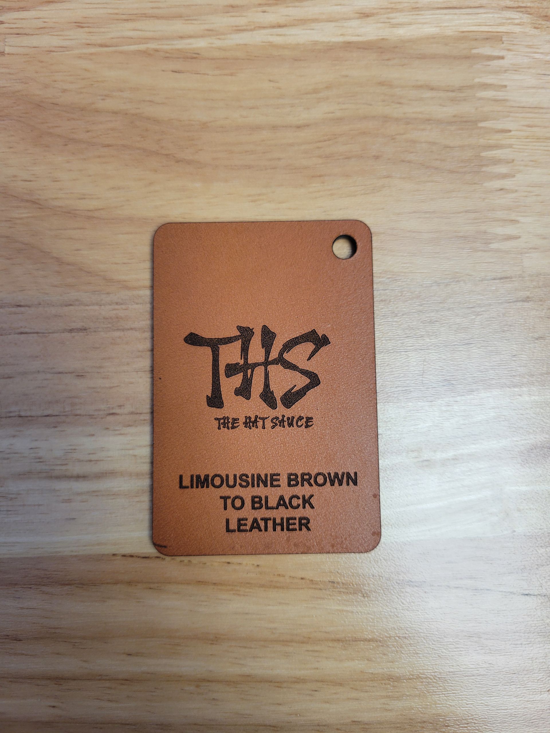 A tag that says limousine brown to black leather is sitting on a wooden table.