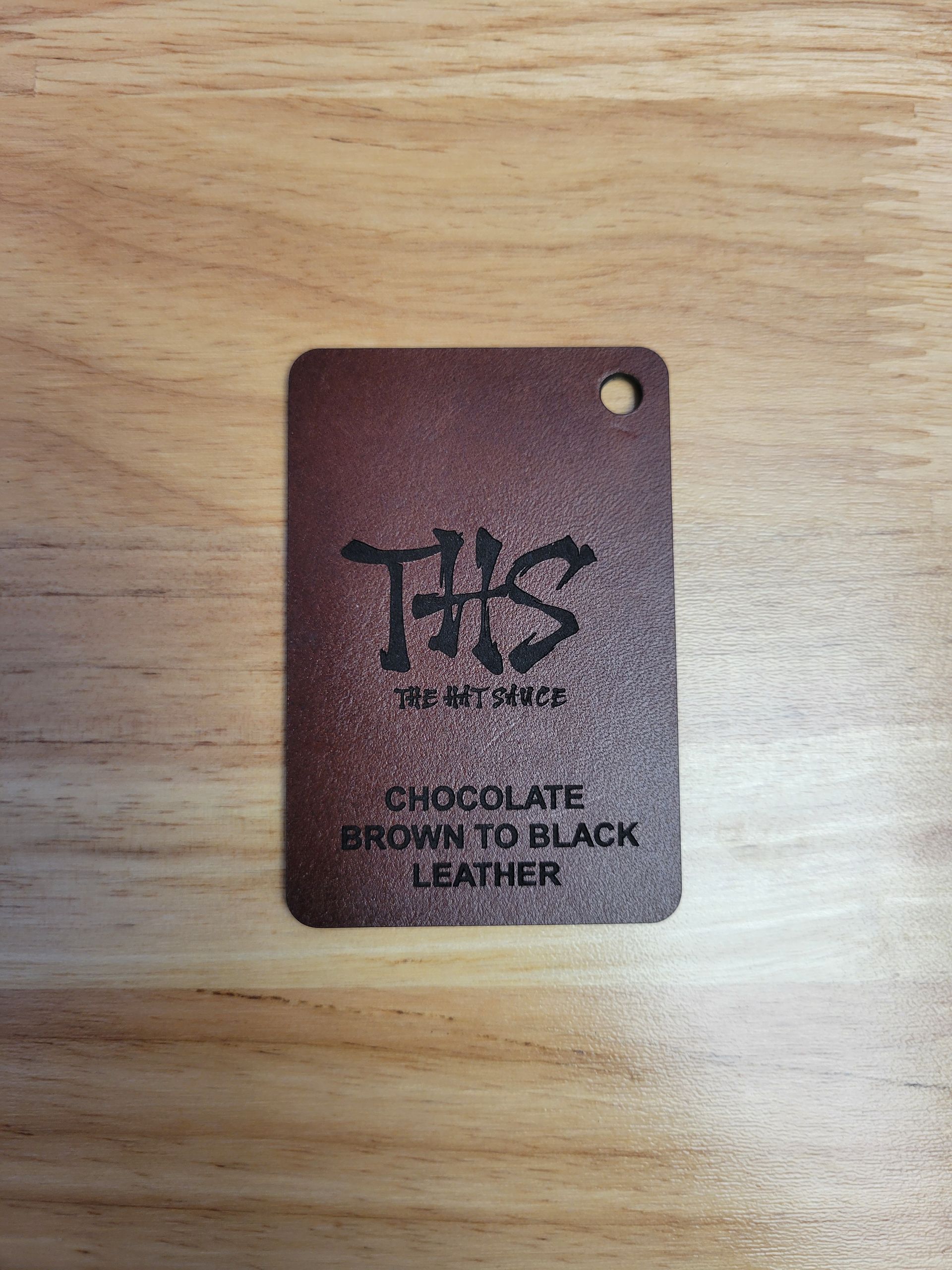 A brown leather tag is sitting on top of a wooden table.