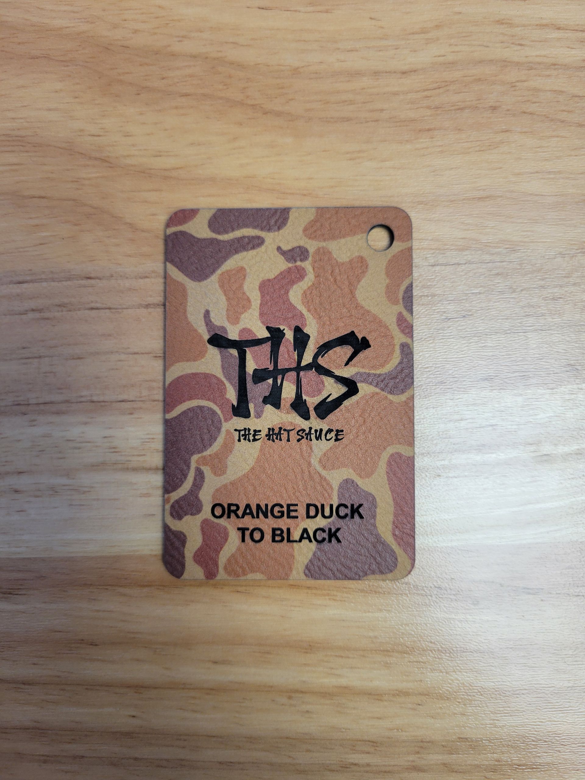 A tag with a camouflage pattern on it is sitting on a wooden table.