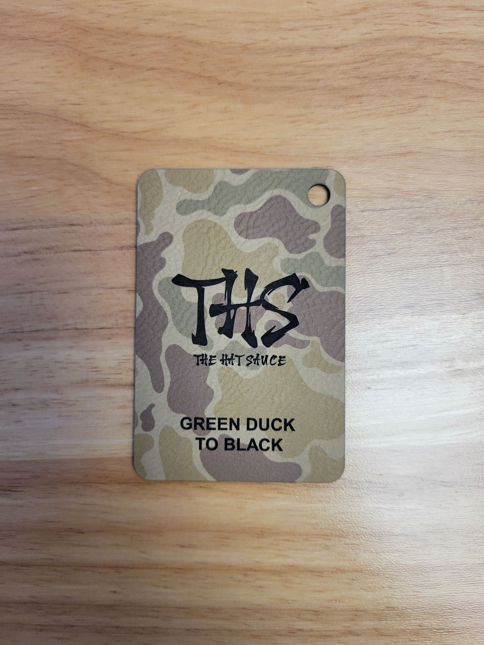 A tag with a camouflage pattern on it is sitting on a wooden table.