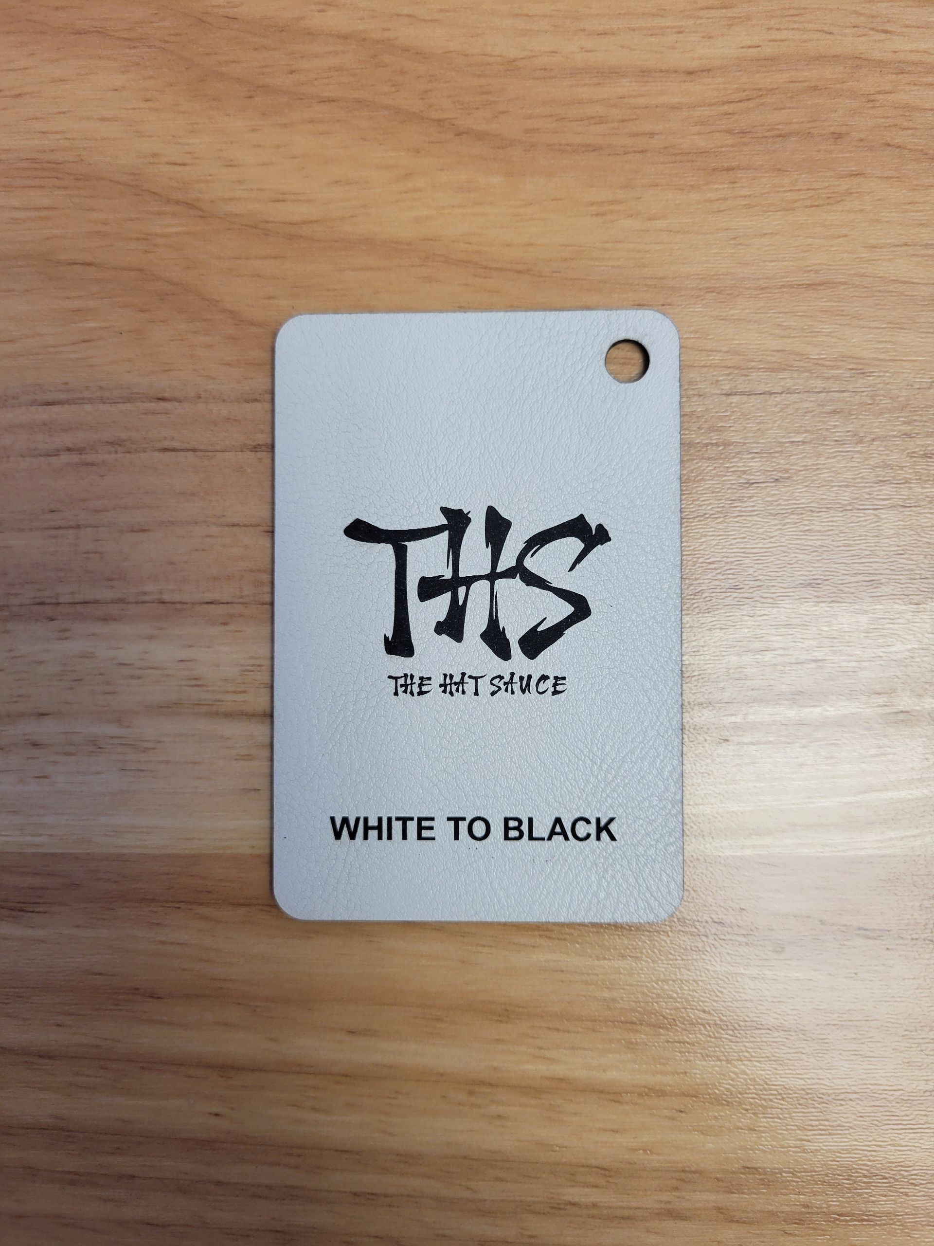 A white to black tag is sitting on a wooden table.