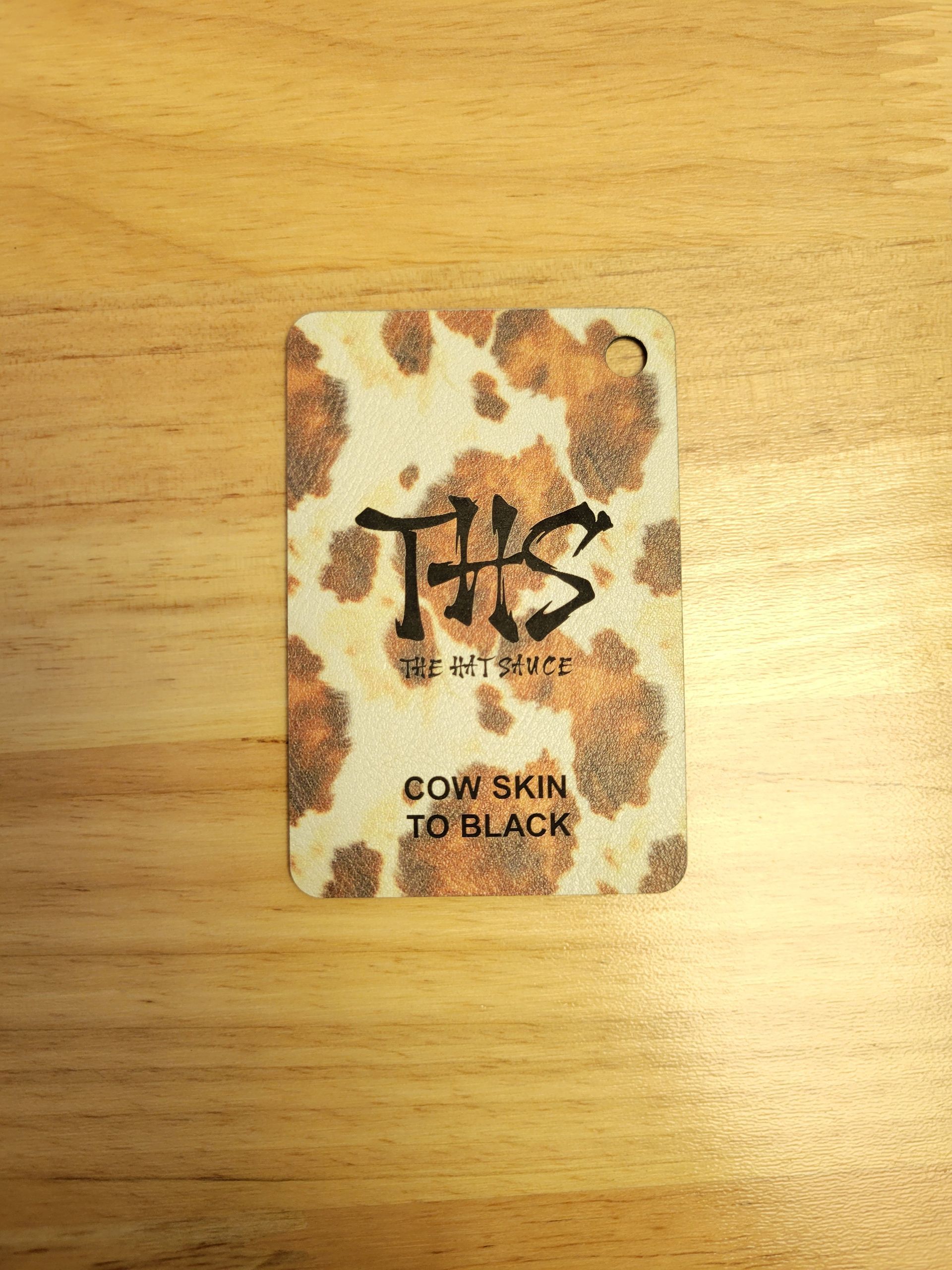 A card with a cow print on it is sitting on a wooden table.