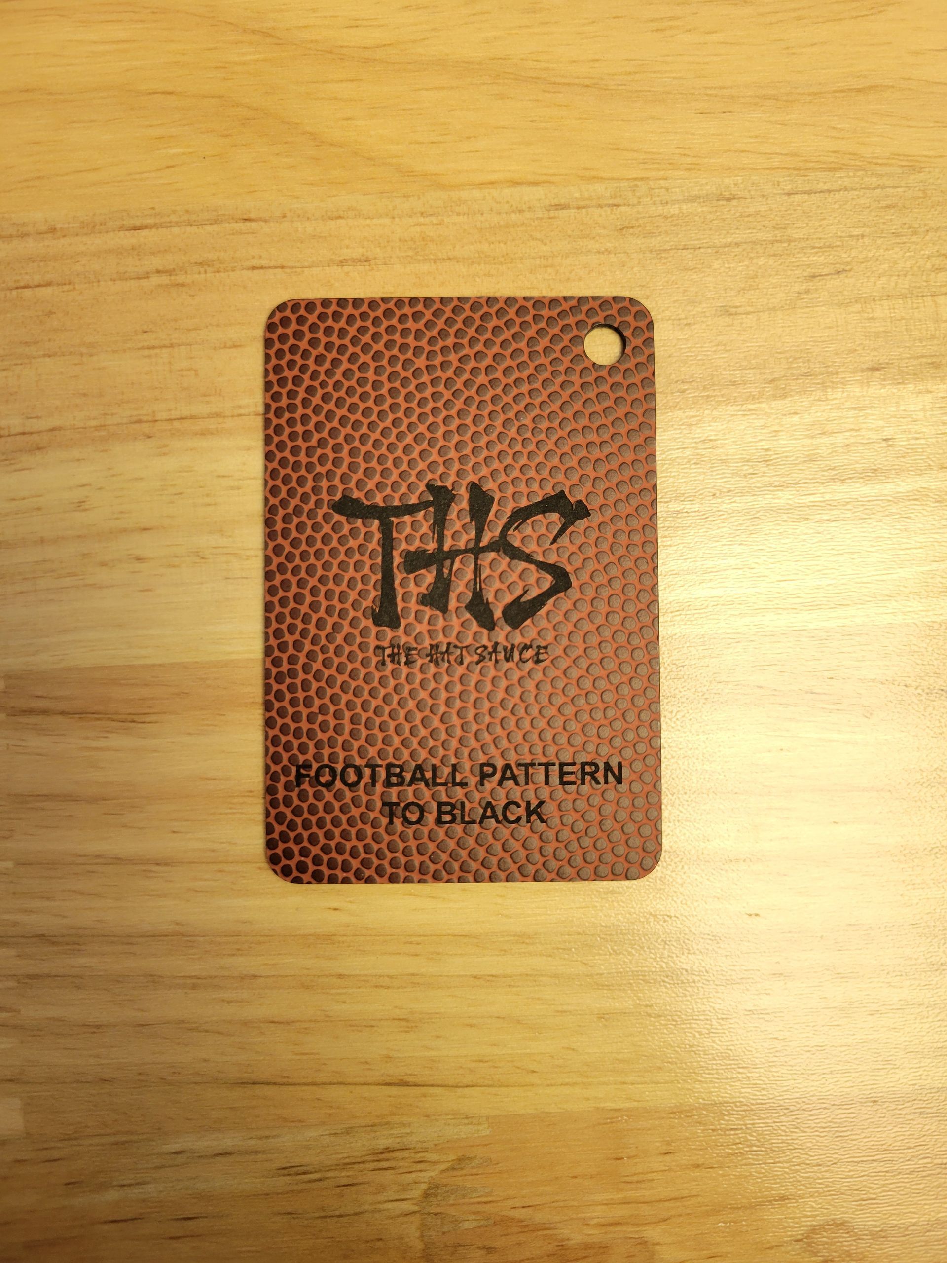 A tag that looks like a football is sitting on a wooden table.