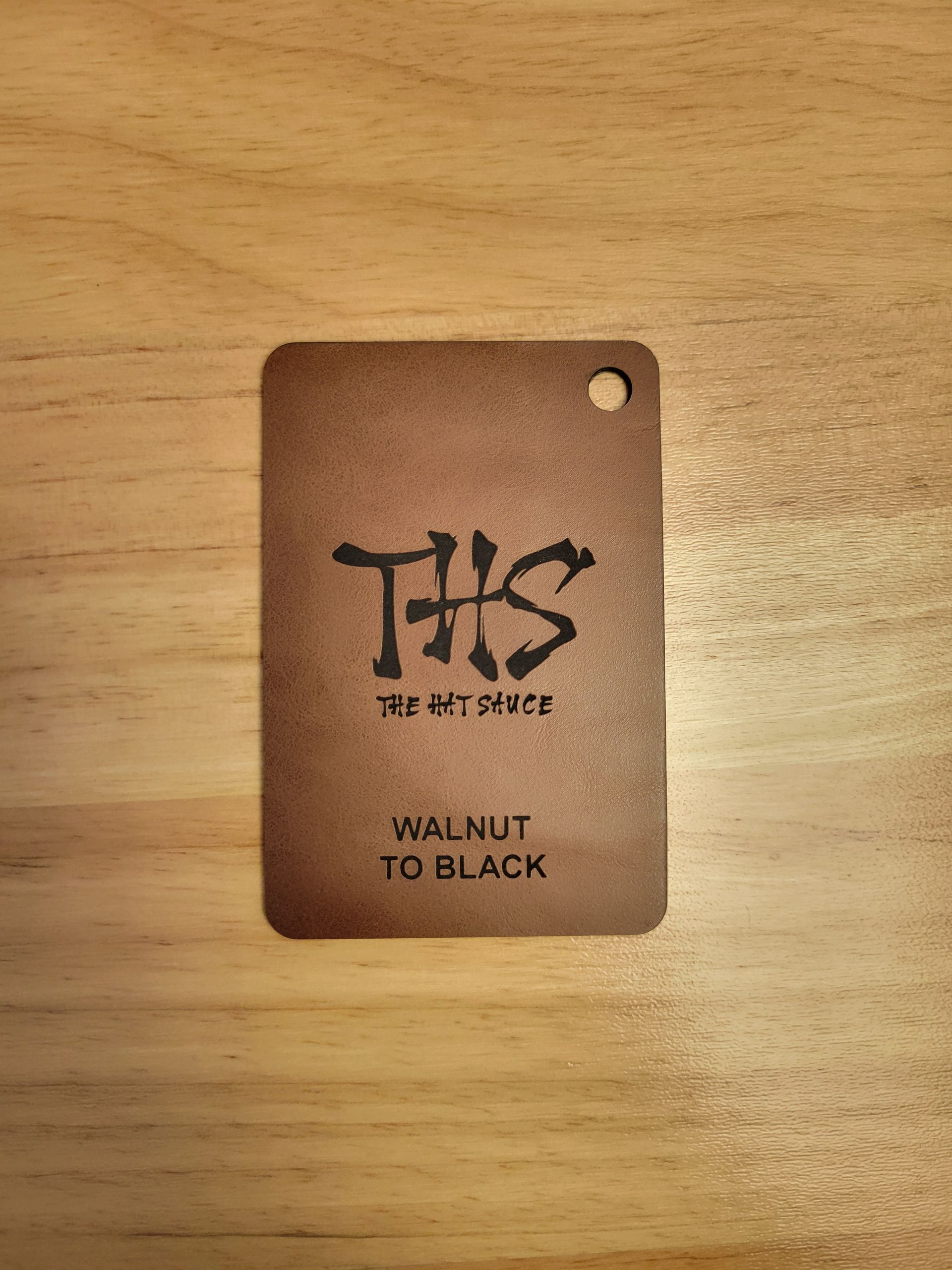 A walnut to black tag is sitting on a wooden table.