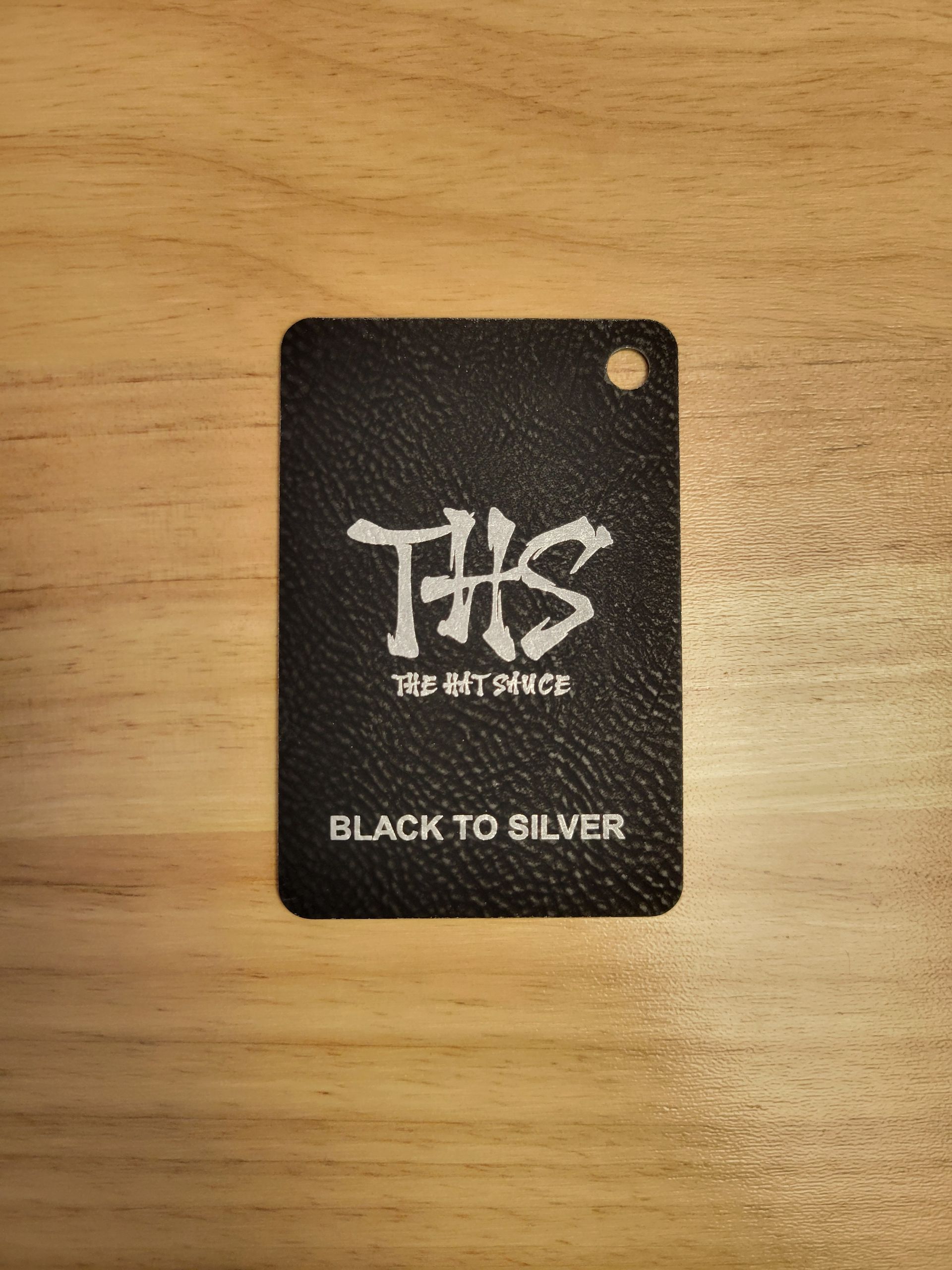 A black tag is sitting on top of a wooden table.