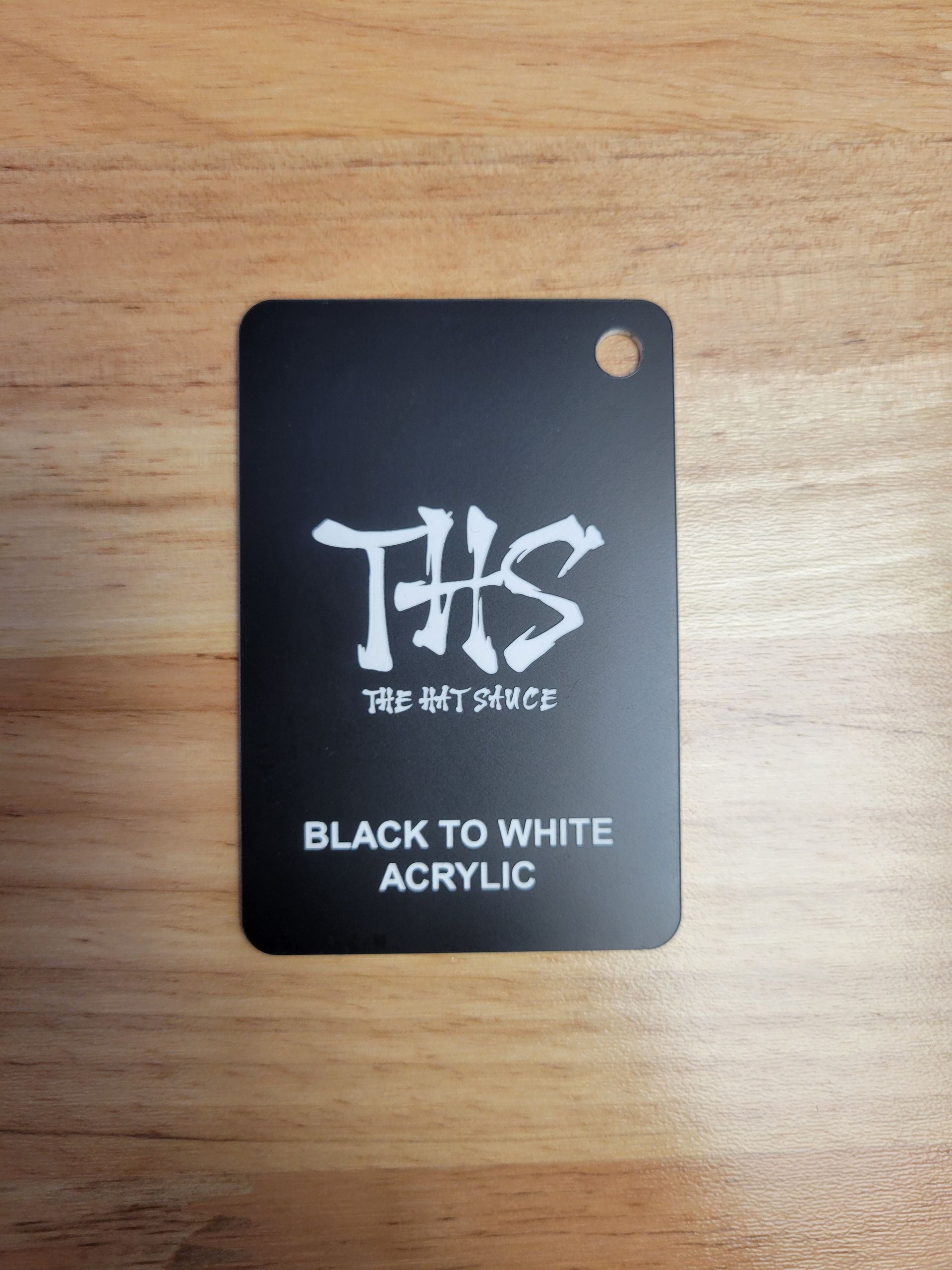 A black to white acrylic tag on a wooden table