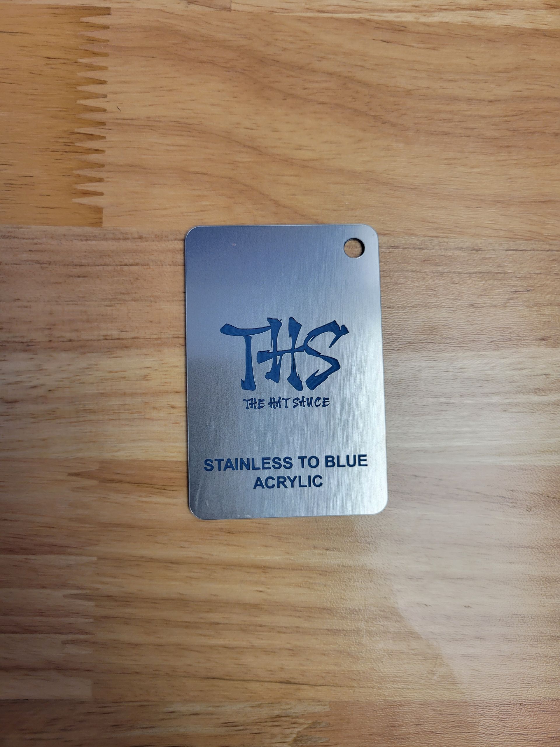 A stainless steel tag is sitting on top of a wooden table.
