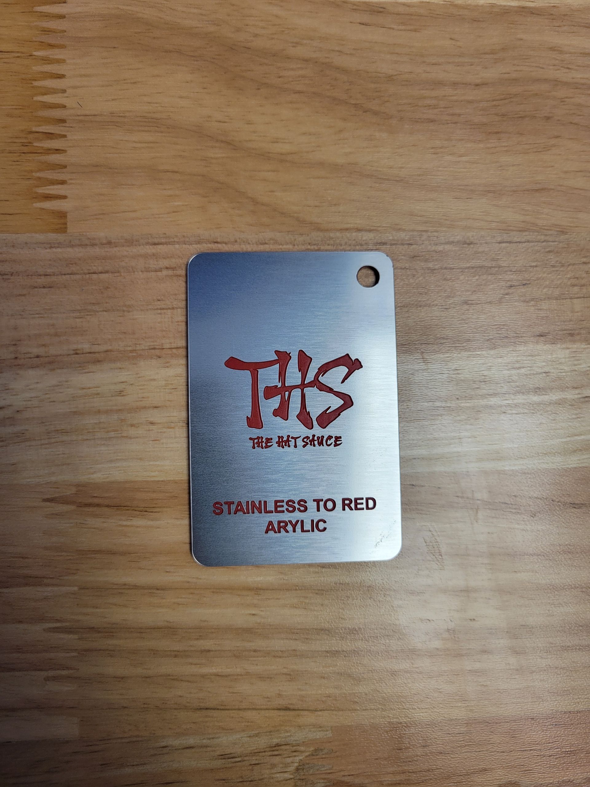 A stainless steel tag is sitting on a wooden table.
