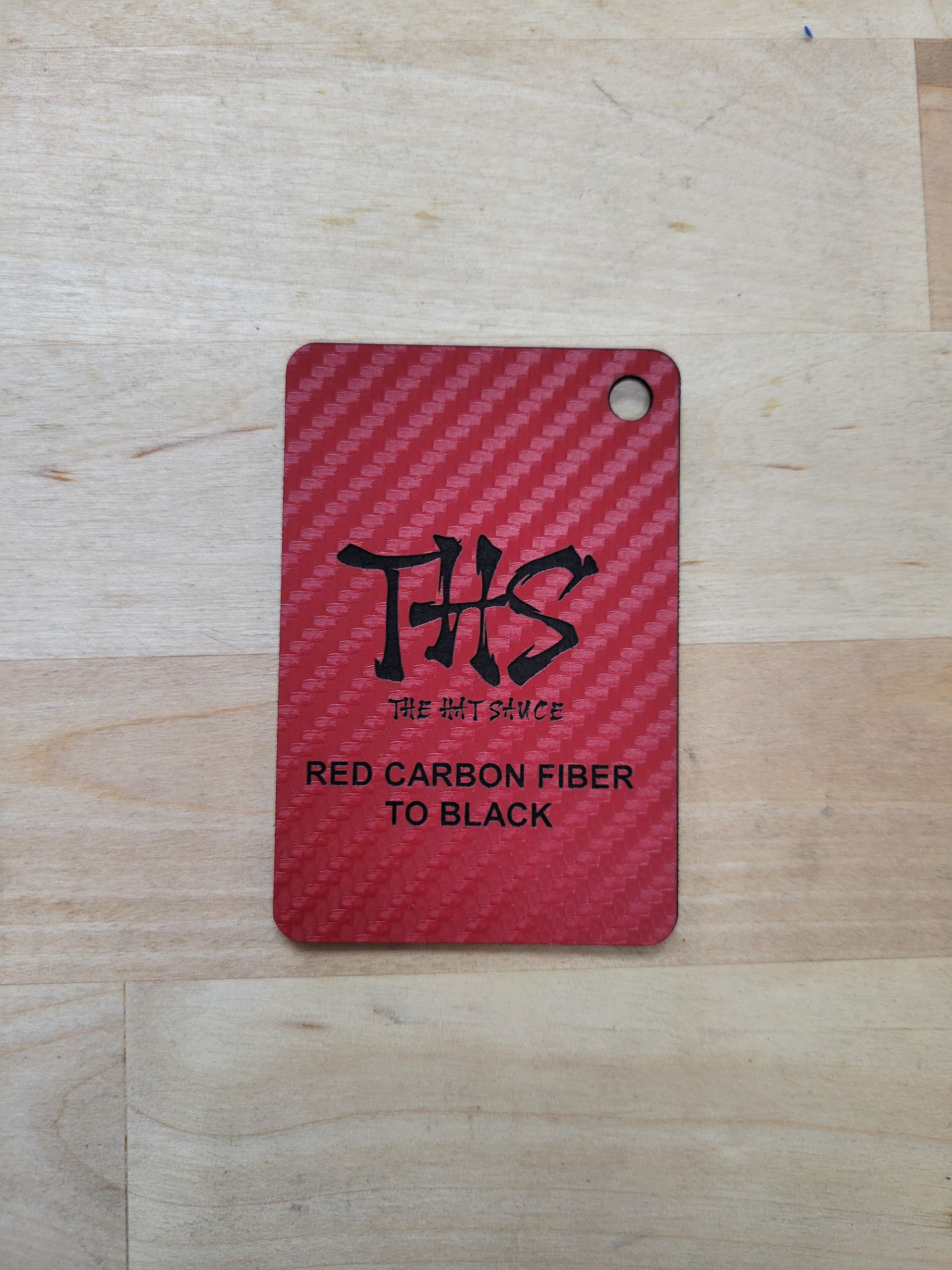 A red carbon fiber tag is sitting on a wooden table