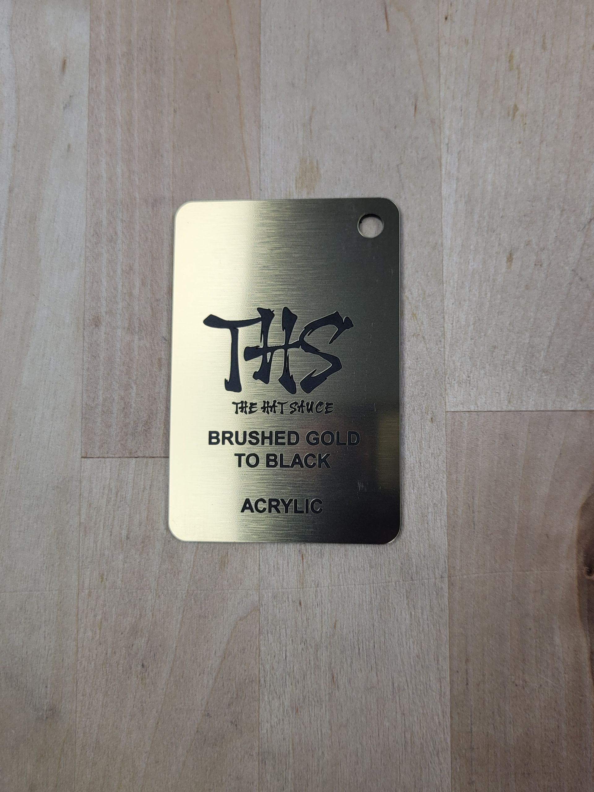 A gold tag that says this brushed gold to black acrylic