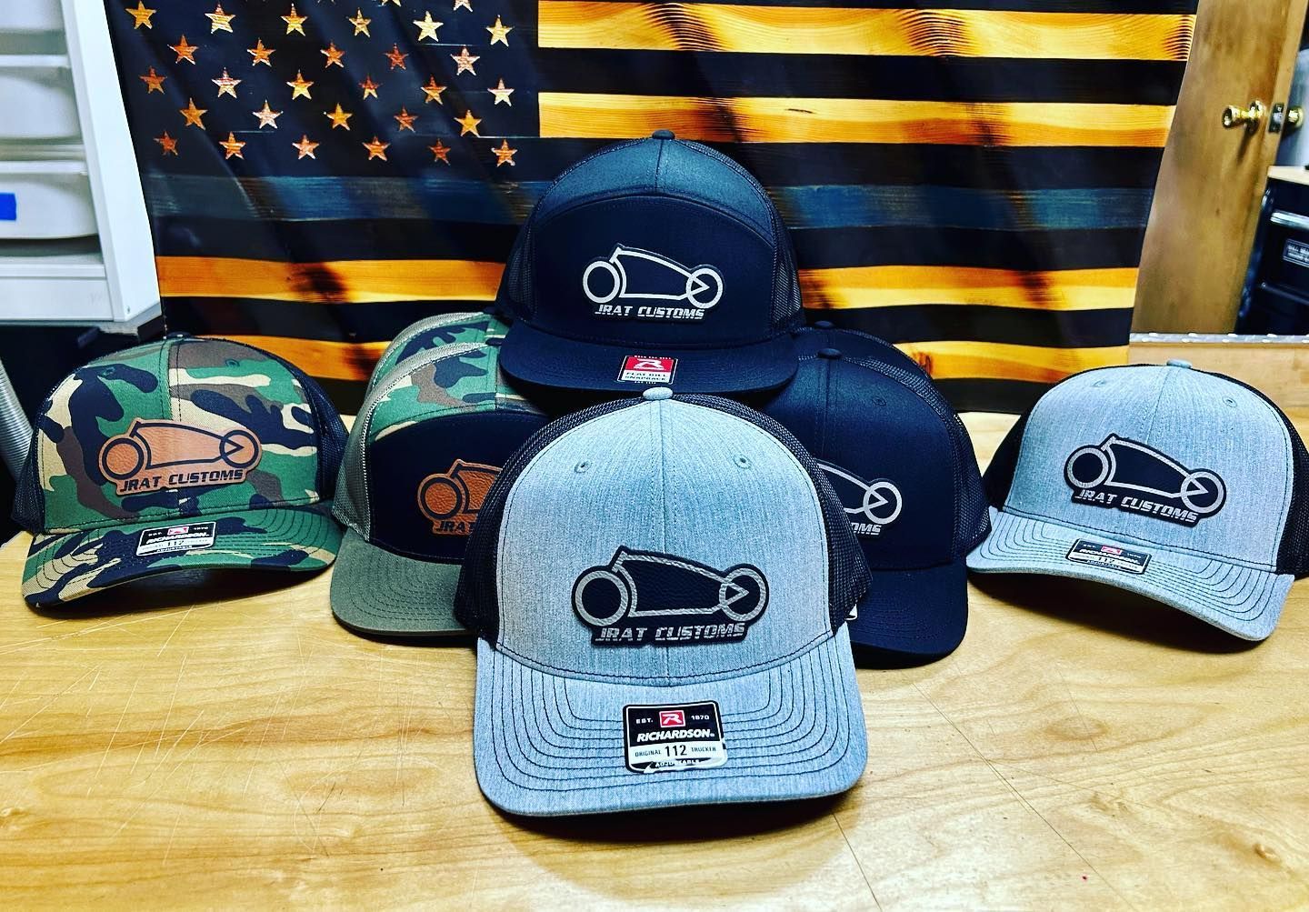 A group of hats are sitting on a wooden table in front of an american flag.