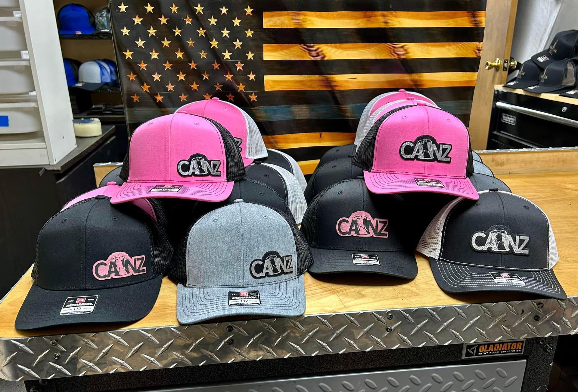 A bunch of hats are sitting on a table in front of an american flag.