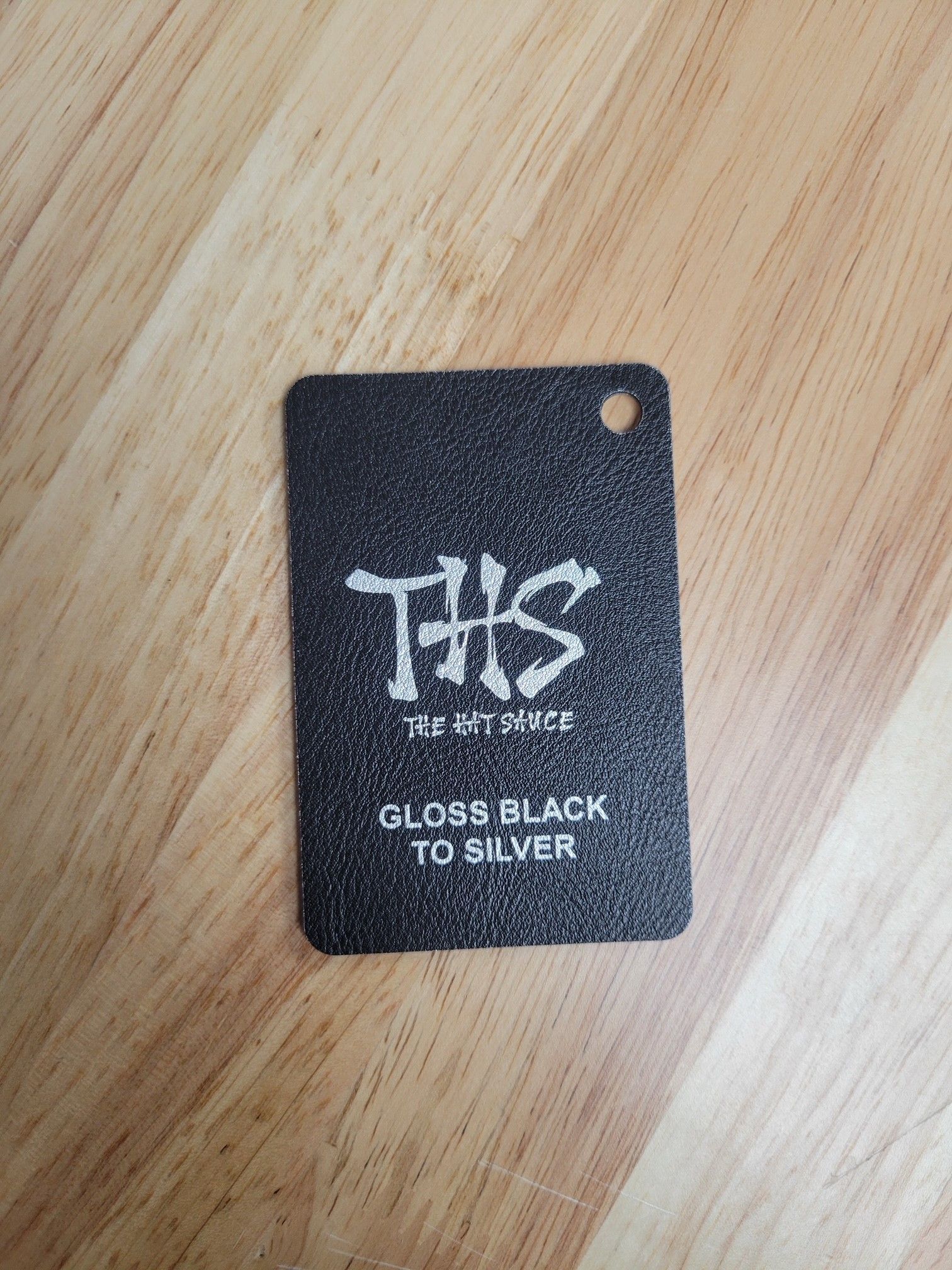 A black tag is sitting on top of a wooden table.