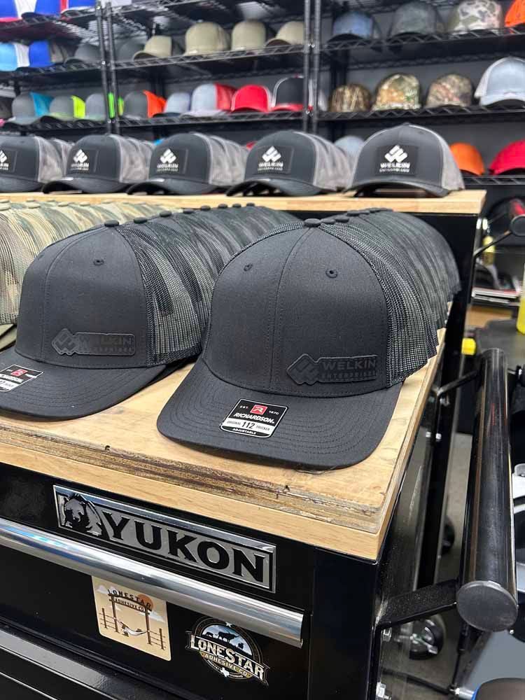 A bunch of black hats are sitting on top of a wooden table.