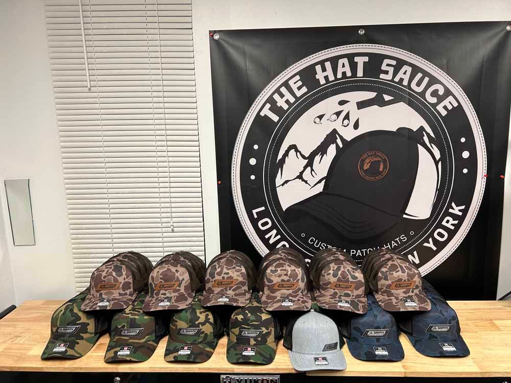 A bunch of hats are sitting on a table in front of a sign that says the hat sauce