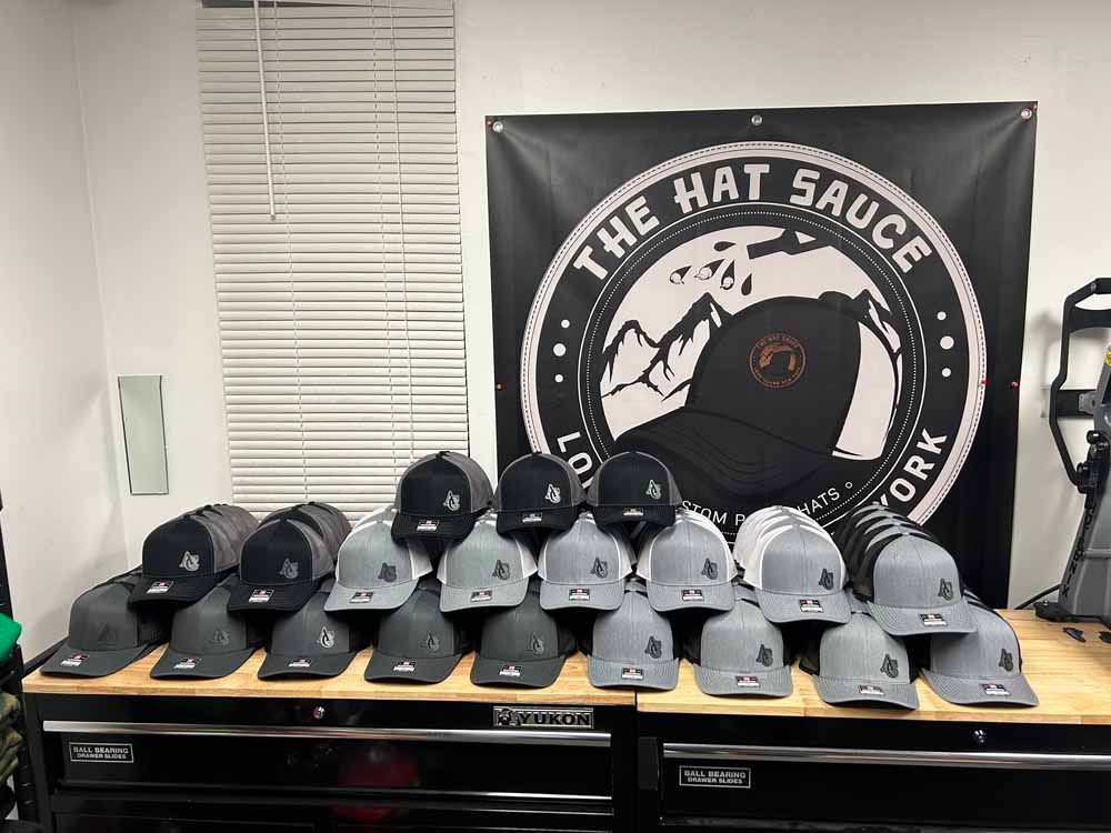 A bunch of hats are sitting on a table in front of a sign that says the hat sauce york