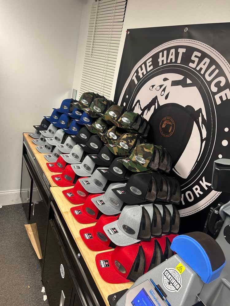 A bunch of hats are sitting on a table in front of a sign that says the hat sauce york.