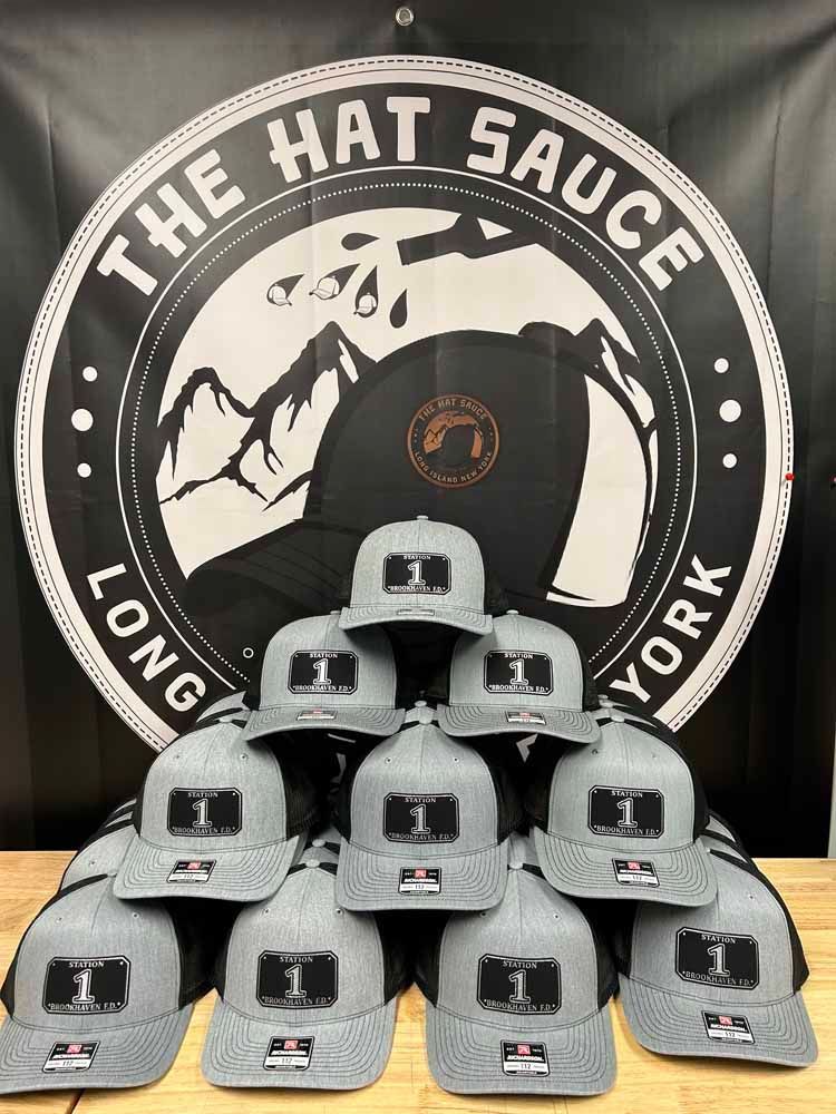 A bunch of hats are stacked on top of each other in front of a sign that says the hat sauce long york