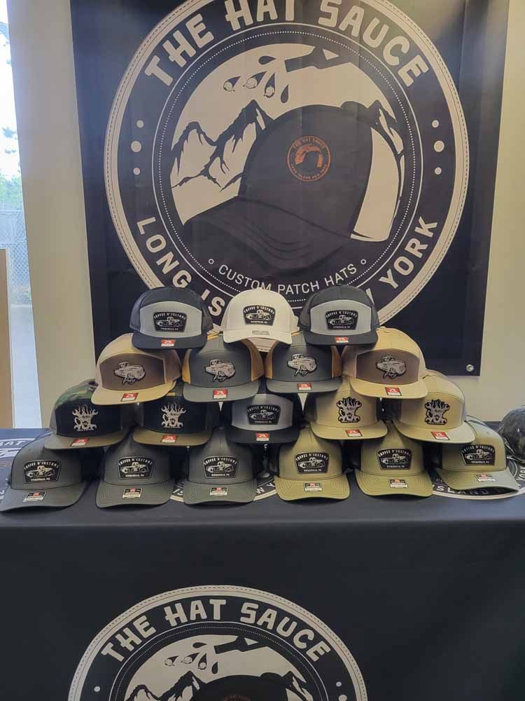 A bunch of hats are sitting on a table in front of a sign that says the hat sauce