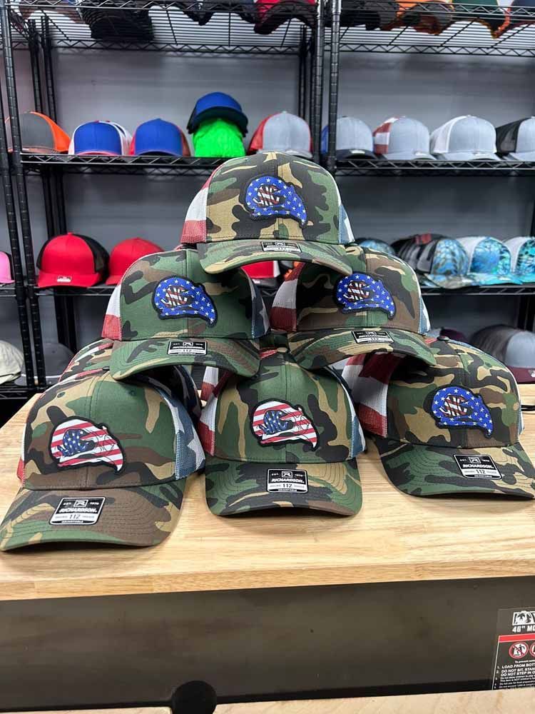 A bunch of baseball caps are sitting on top of a wooden table.
