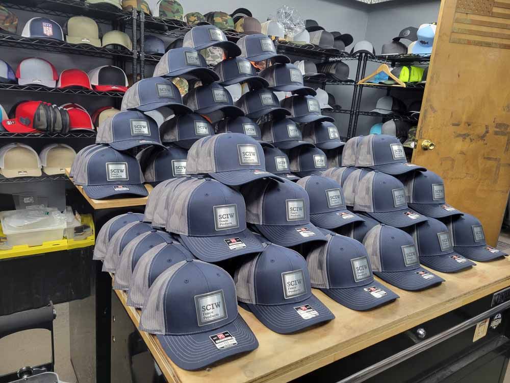 A bunch of baseball caps are stacked on top of each other on a table.