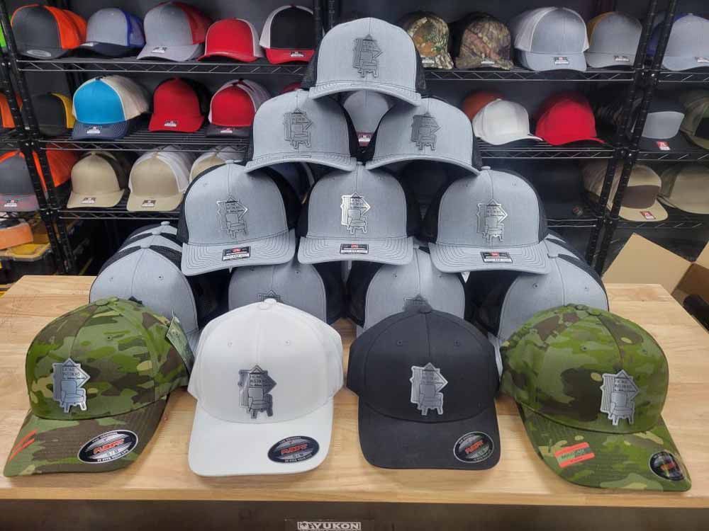 A bunch of baseball caps are stacked on top of each other on a table.