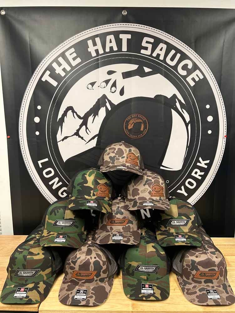 A bunch of hats are sitting on a table in front of a sign that says the hat sauce long york