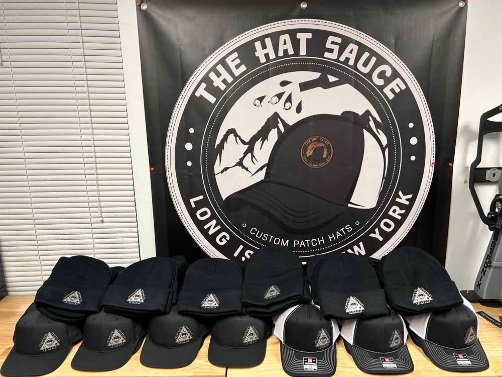 A bunch of hats are sitting in front of a sign that says the hat sauce