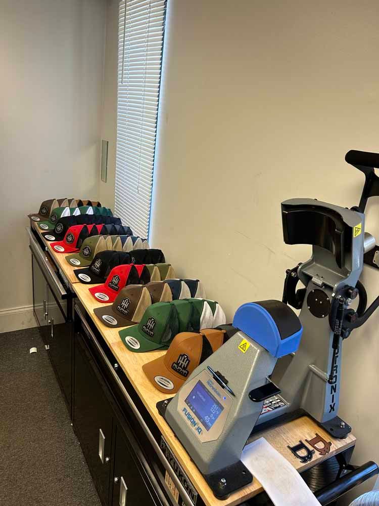 A row of hats are sitting on a table next to a machine.