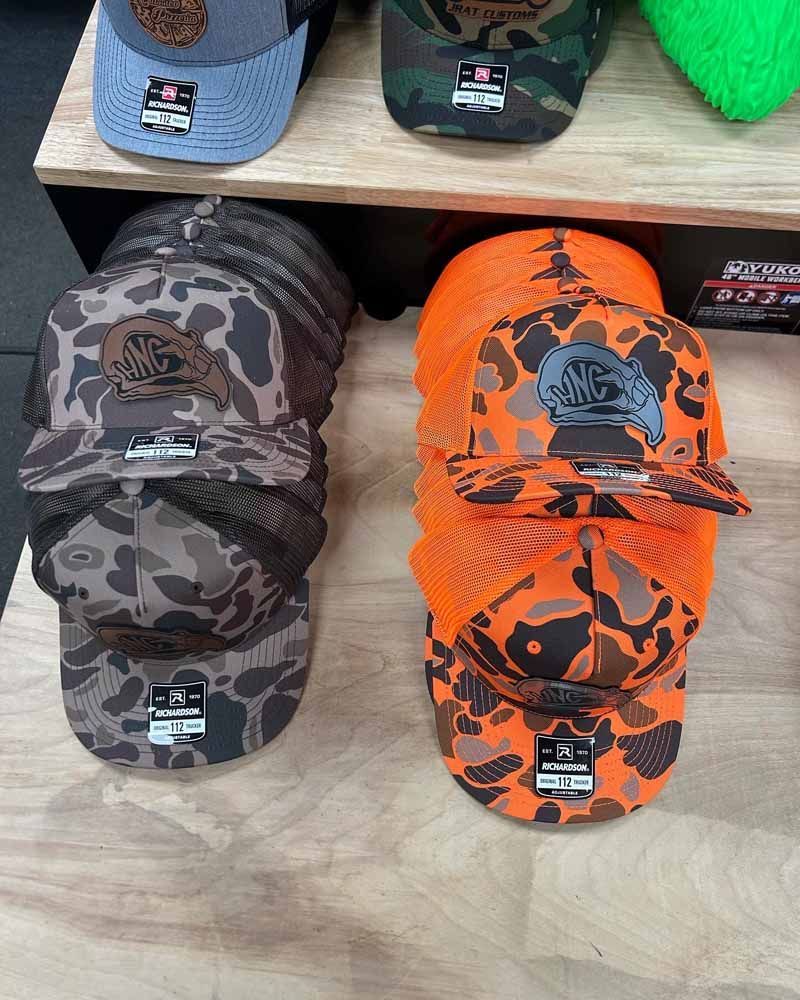 A bunch of hats are stacked on top of each other on a wooden table.