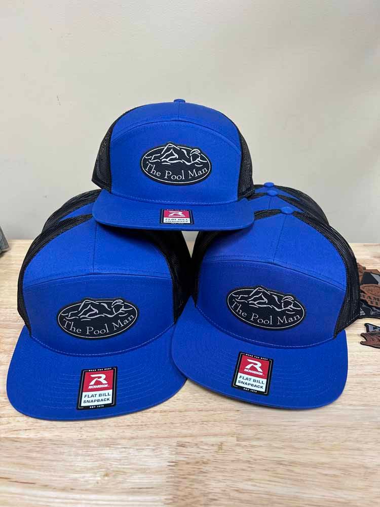 Three blue hats are stacked on top of each other on a wooden table.